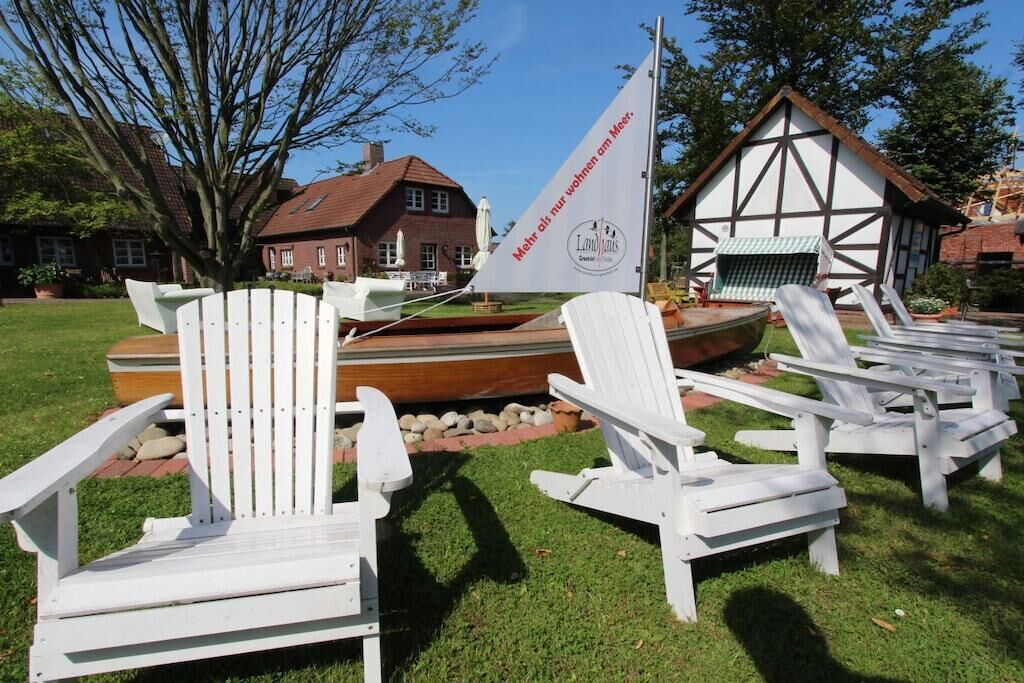Terras met Adirondack stoelen, een zeilboot en een traditioneel gebouw met een wit en bruin gevel.