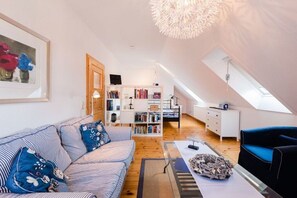 Un appartement moderne de style « loft », avec un lit en mezzanine, un canapé à rayures, une bibliothèque et un coin repas.