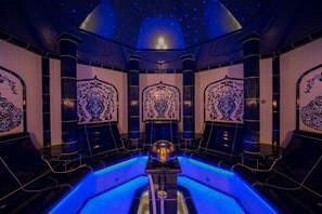 Une chambre luxueuse dotée d’un plafond étoilé, de motifs décoratifs élaborés sur les murs et d’un objet sphérique placé au centre.