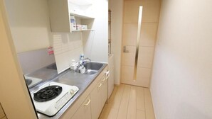 A compact kitchen with a stove, sink, and cabinets. - Sakura Court Ebisu (Shibuya)