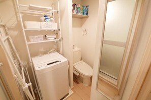 Ein kleines Badezimmer mit Toilette, Ablagefläche für Toilettenartikel und einer Waschmaschine.