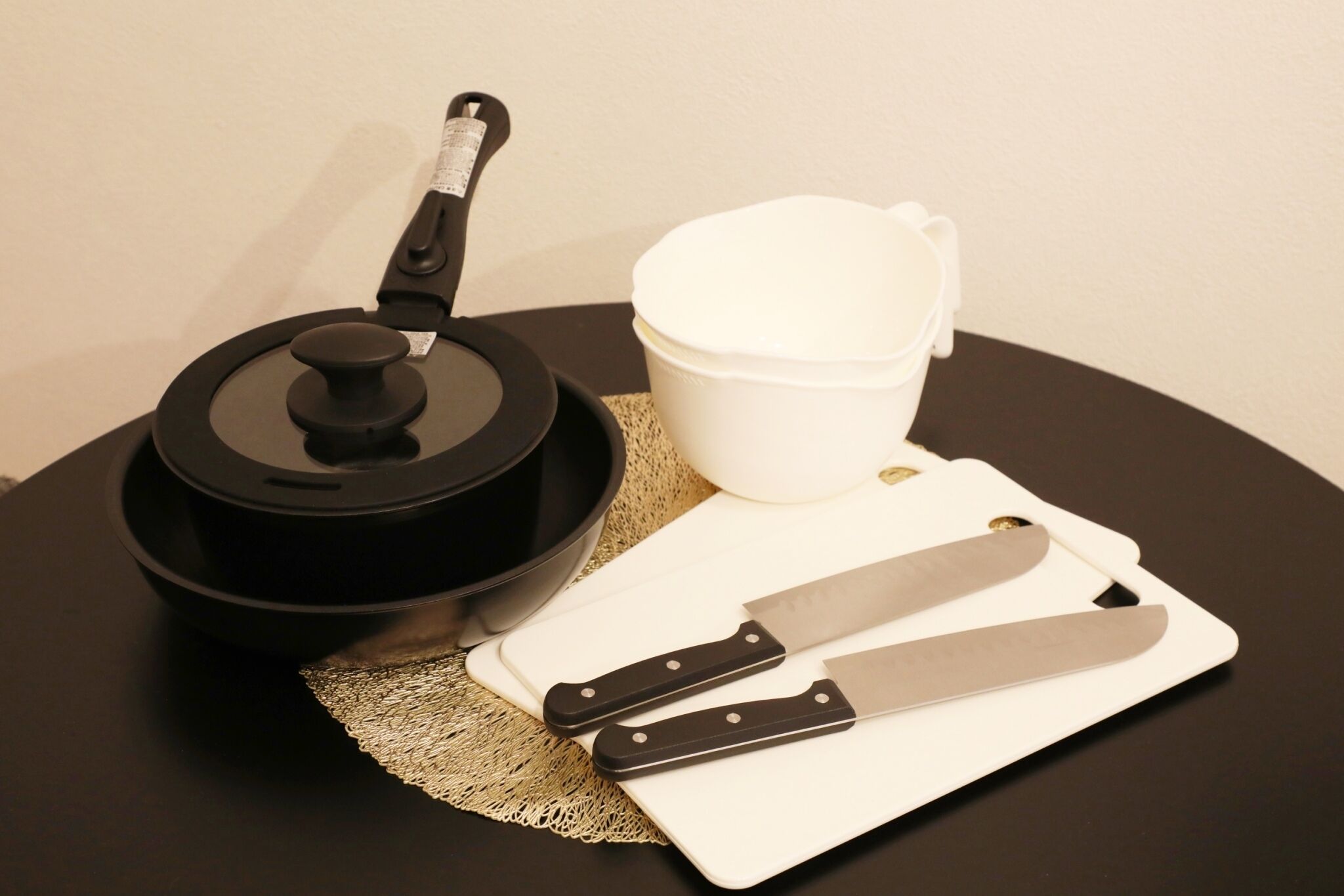 A kitchen setup with a pot, a cutting board, a knife, and a cup on a round table.