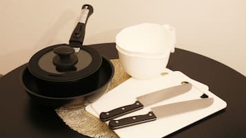 A kitchen setup with a pot, a cutting board, a knife, and a cup on a round table.