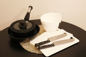 A kitchen setup with a pot, a cutting board, a knife, and a cup on a round table. - Sakura Court Ebisu (Shibuya)