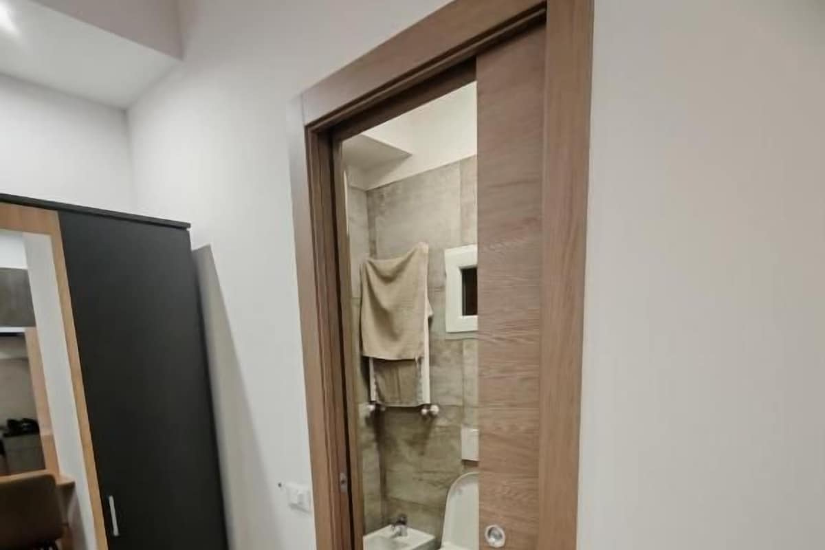 A modern bathroom with a wooden floor, a toilet, and a shower area.