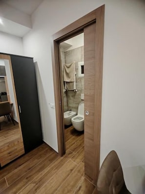A modern bathroom with a wooden floor, a toilet, and a shower area. - B&B RioReno (CITTÀ METROPOLITANA DI BOLOGNA)