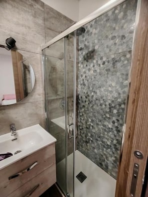 A bathroom with a glass shower enclosure, a wooden vanity with a sink, and a mirror. - B&B RioReno (CITTÀ METROPOLITANA DI BOLOGNA)