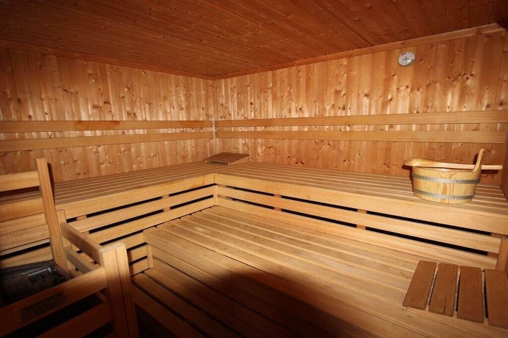 Un sauna avec des bancs en bois et un seau en bois.
