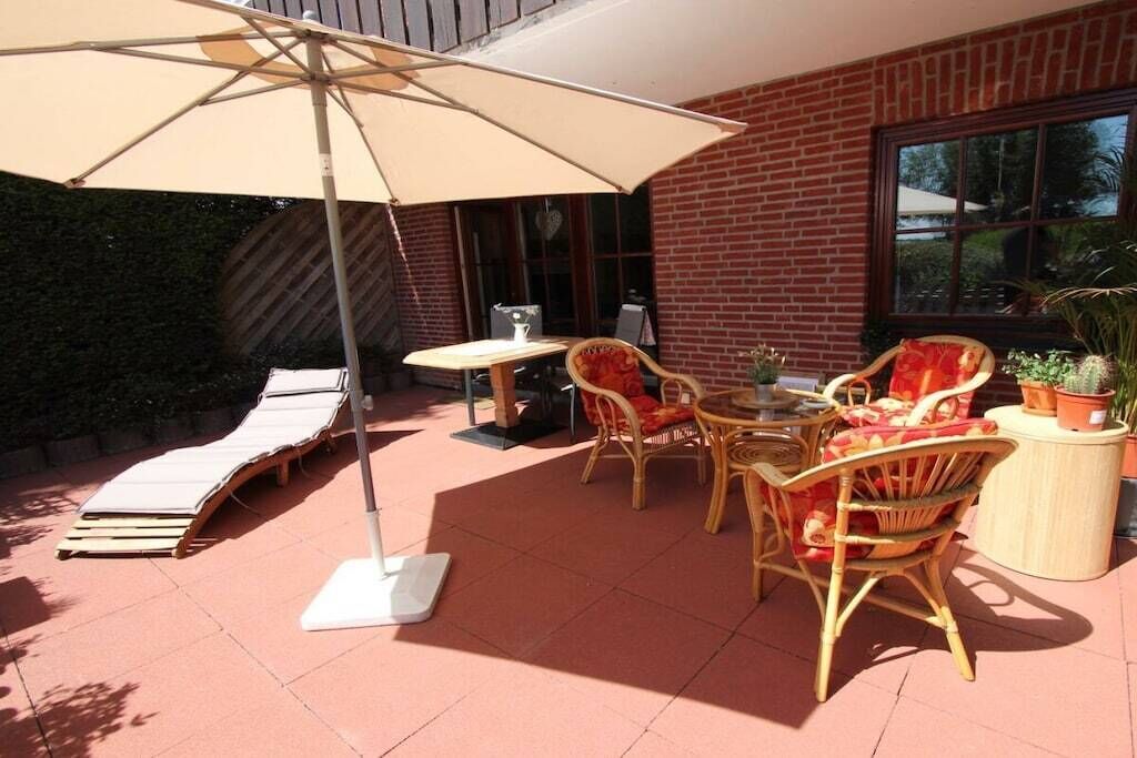 Eine Terrasse im Freien mit Tisch, Stühlen, Sonnenschirm und Liege.