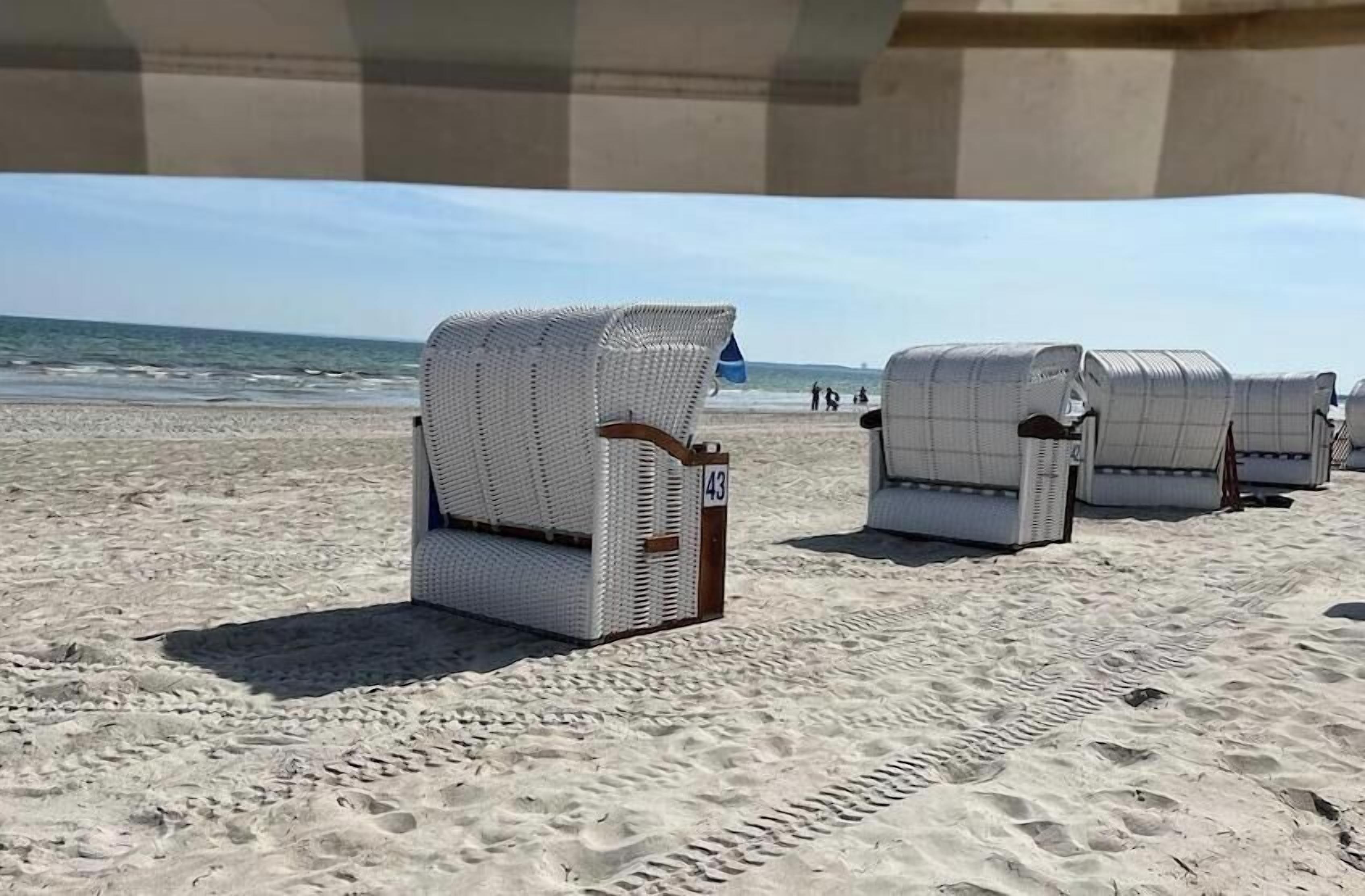 Beach chairs with numbers on them, arranged on a sandy beach with the ocean in the background.
