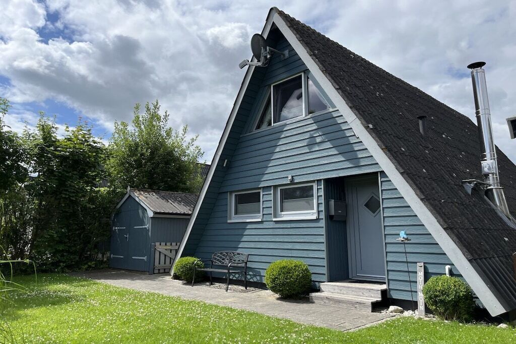 A blue house with a sloped roof, a satellite dish, and a chimney.