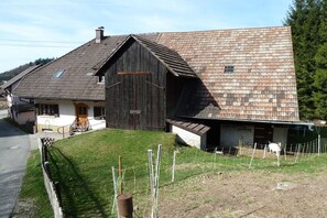 A rustic barn with a sloped roof, a small adjacent building, and a fenced yard. - Holiday home with 2 bedrooms (Malsburg Marzell)