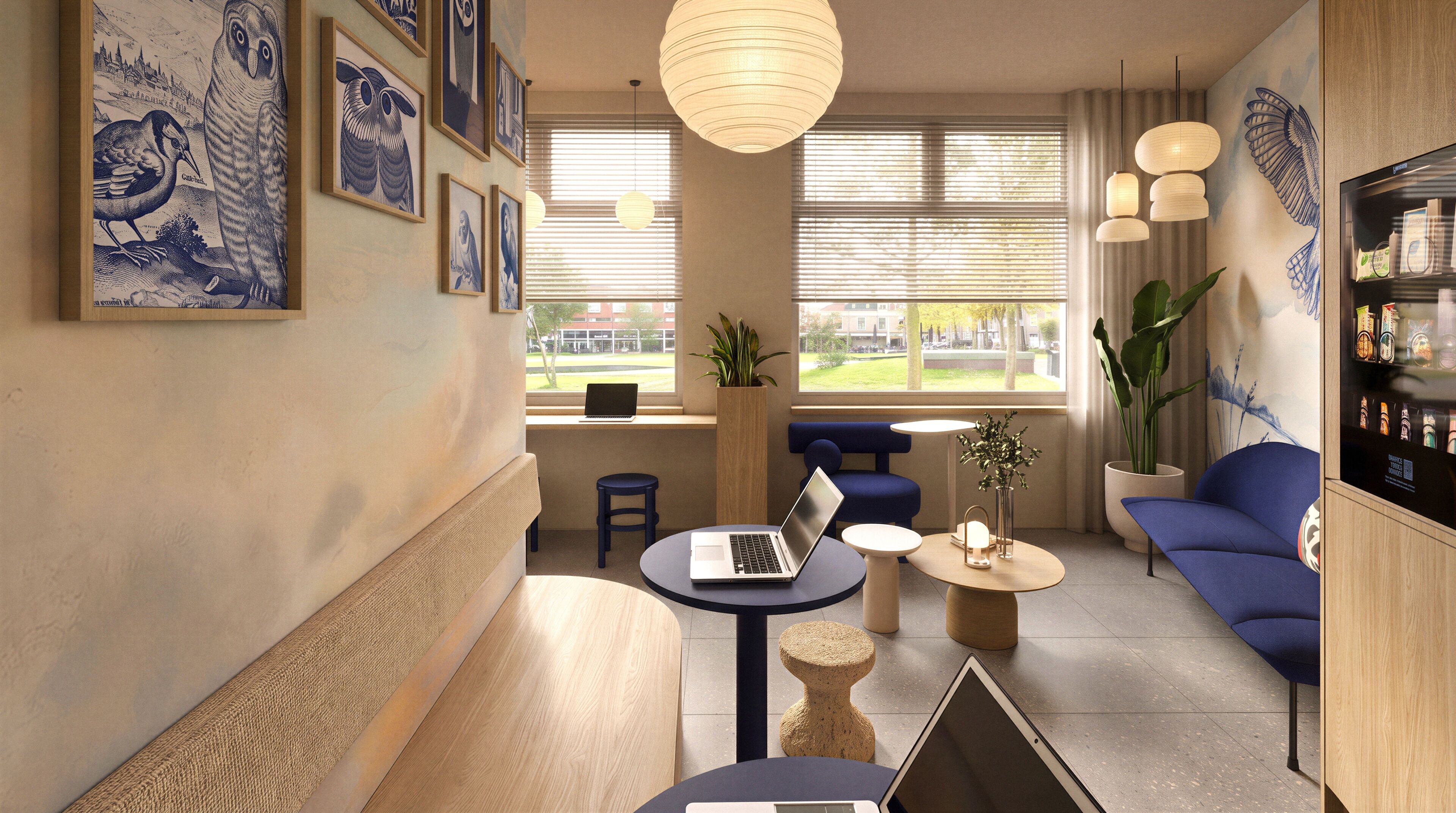 A modern lounge area with a laptop on a table, a potted plant, and a seating area with blue sofas.