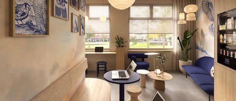 A modern lounge area with a laptop on a table, a potted plant, and a seating area with blue sofas.