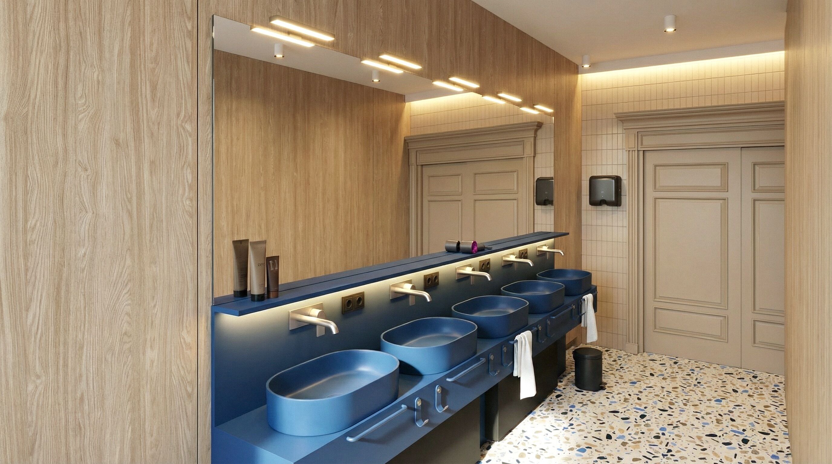 Un baño moderno con pared de madera, un espejo y una hilera de lavamanos con lavabos azules.