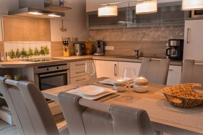 A modern kitchen with a dining area, equipped with stainless steel appliances, a stone backsplash, and a casual seating arrangement. - Holiday apartment with 2 bedrooms (Norden)