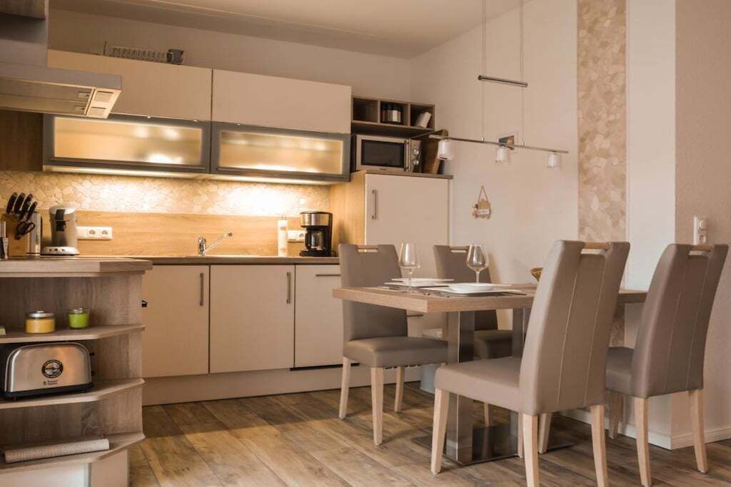 Een moderne keuken met een eethoek, voorzien van een magnetron, koffiezetapparaat en broodrooster.