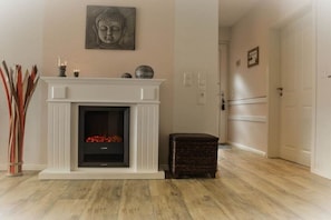A room with a fireplace, a Buddha statue, and a wicker stool. - Holiday apartment with 2 bedrooms (Norden)