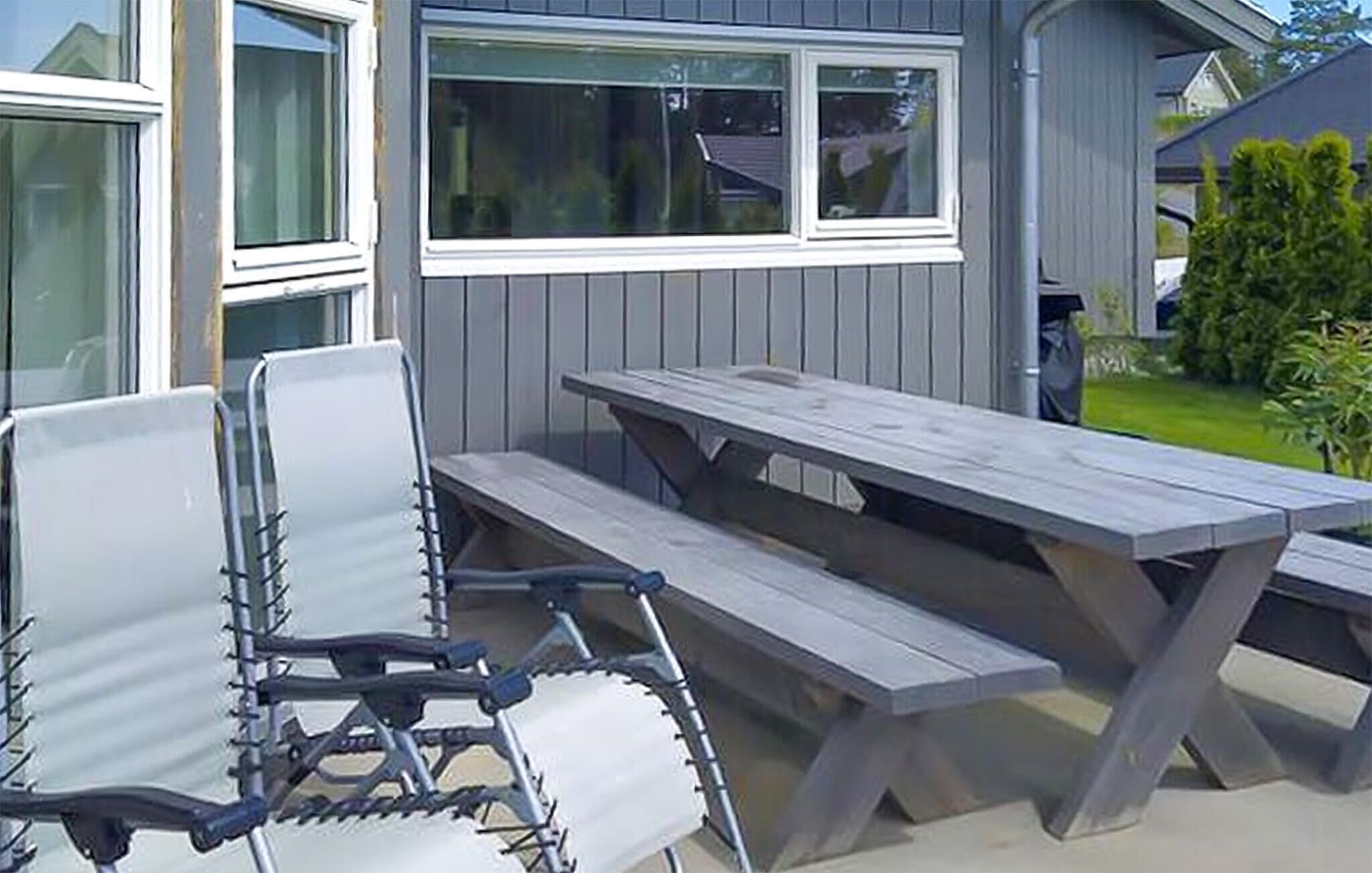 An outdoor seating area with a wooden picnic table and metal chairs.