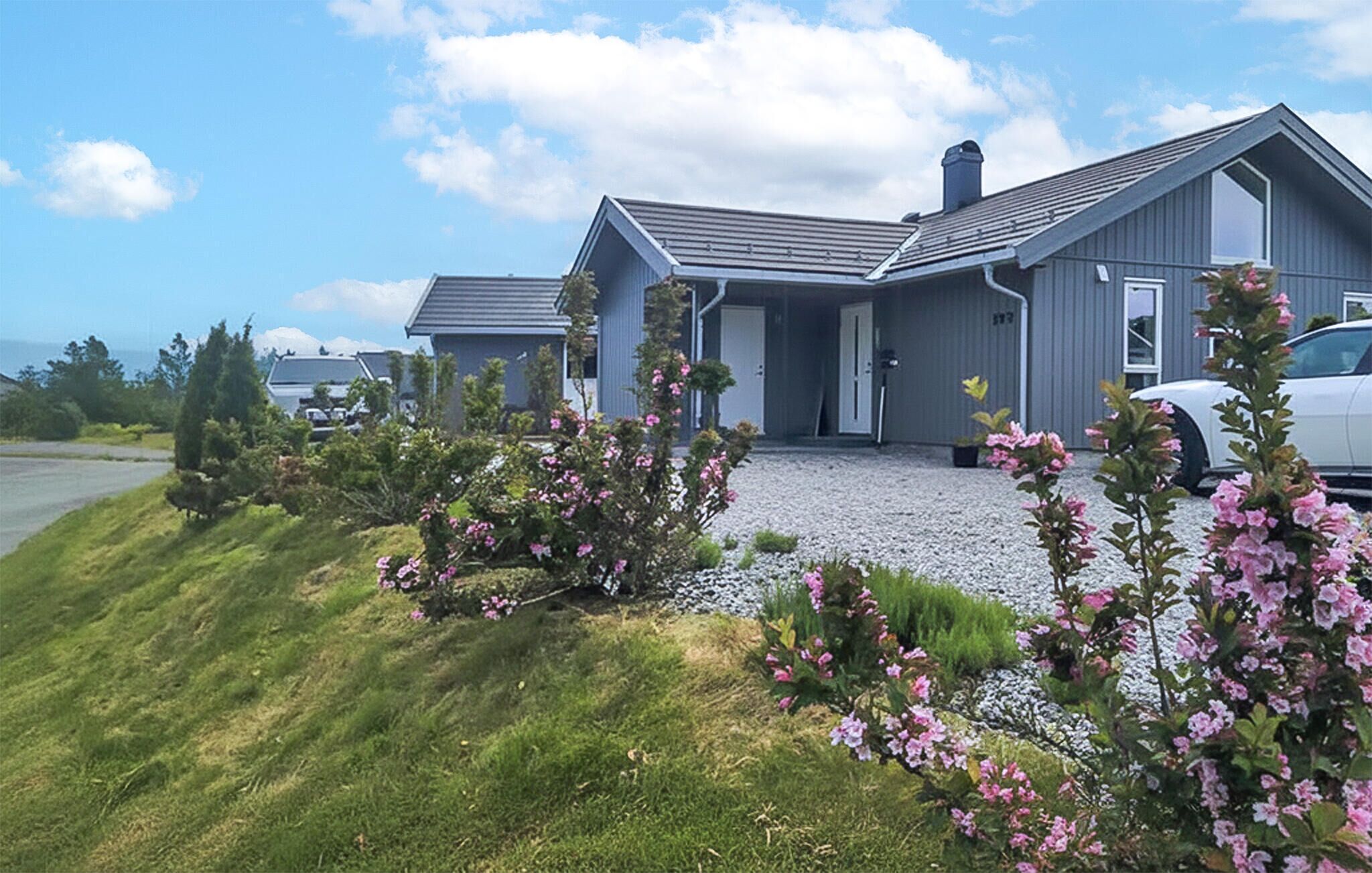 A modern two-story house with a gravel driveway and a car parked in the driveway.
