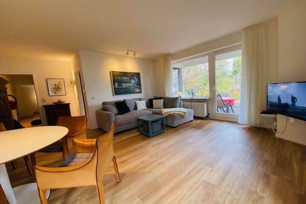 Un salon moderne comprenant un canapé, des fauteuils, une table basse et un téléviseur.