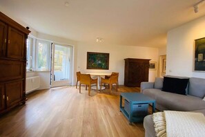 A living room with a sofa, a table with chairs, a cabinet, and a painting on the wall. - Holiday apartment with 2 bedrooms (Lübeck)