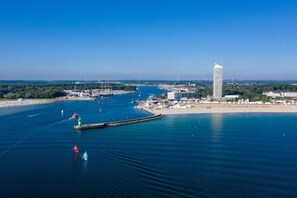 A coastal cityscape with a prominent tall building, a marina with boats, and a clear blue sky. - Holiday apartment with 2 bedrooms (Lübeck)