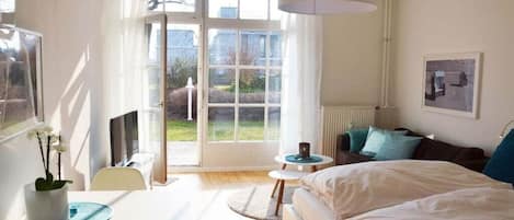 Une chambre à coucher avec un lit, un bureau, une chaise, une fenêtre et une porte.