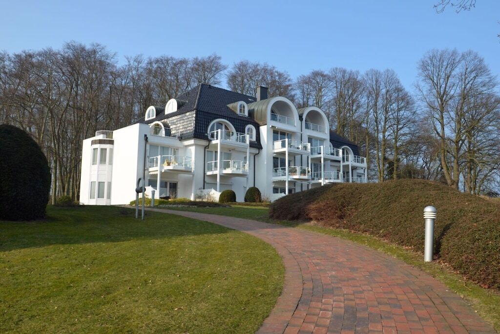 Un bâtiment moderne doté de nombreux balcons et d’un chemin en briques menant à l’entrée.