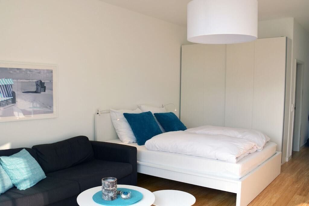 A modern bedroom with a bed, a sofa, a small table, and a white wardrobe.