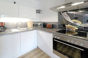 Eine moderne Küche mit weißen Schränken, einem Edelstahlherd, einer Mikrowelle und einem Toaster.