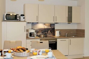Cuina compacta amb microones, cafetera i rentapelats. Hi ha una taula de dinar amb articles per a l'esmorzar i un cistell de pa.