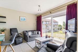 A modern living room with a sofa, chairs, a coffee table, and a large window with curtains. - Green Garden 9 / 0105 (De Haan)