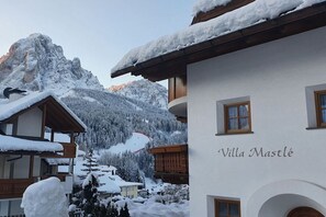 A building named 'Villa Mastlé' with a snow-covered roof and mountainous background.