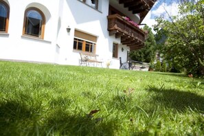 A white building with a balcony and a grassy lawn.