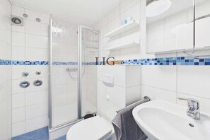 Un bagno con doccia, WC e lavandino.
