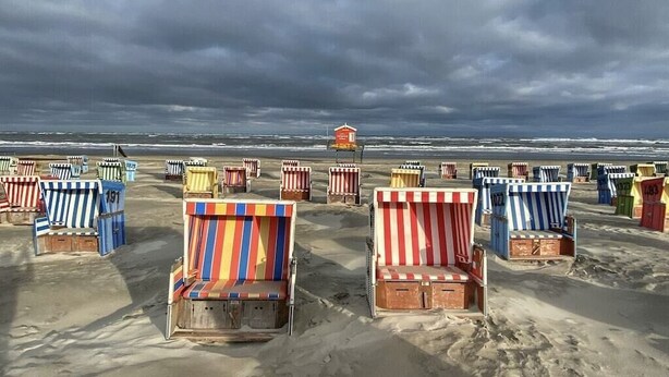 A beach with numerous colorful beach chairs and a lifeguard tower. - Holiday apartment with 2 bedrooms (Langeoog)