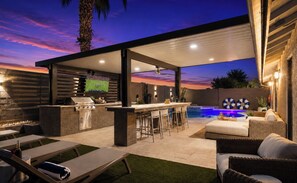 An outdoor patio with a bar, seating, and a pool.