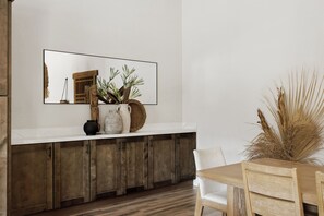 Eine moderne Küche mit weißer Arbeitsplatte, Holzschränken und einem Essbereich inklusive Holztisch und Stühlen.