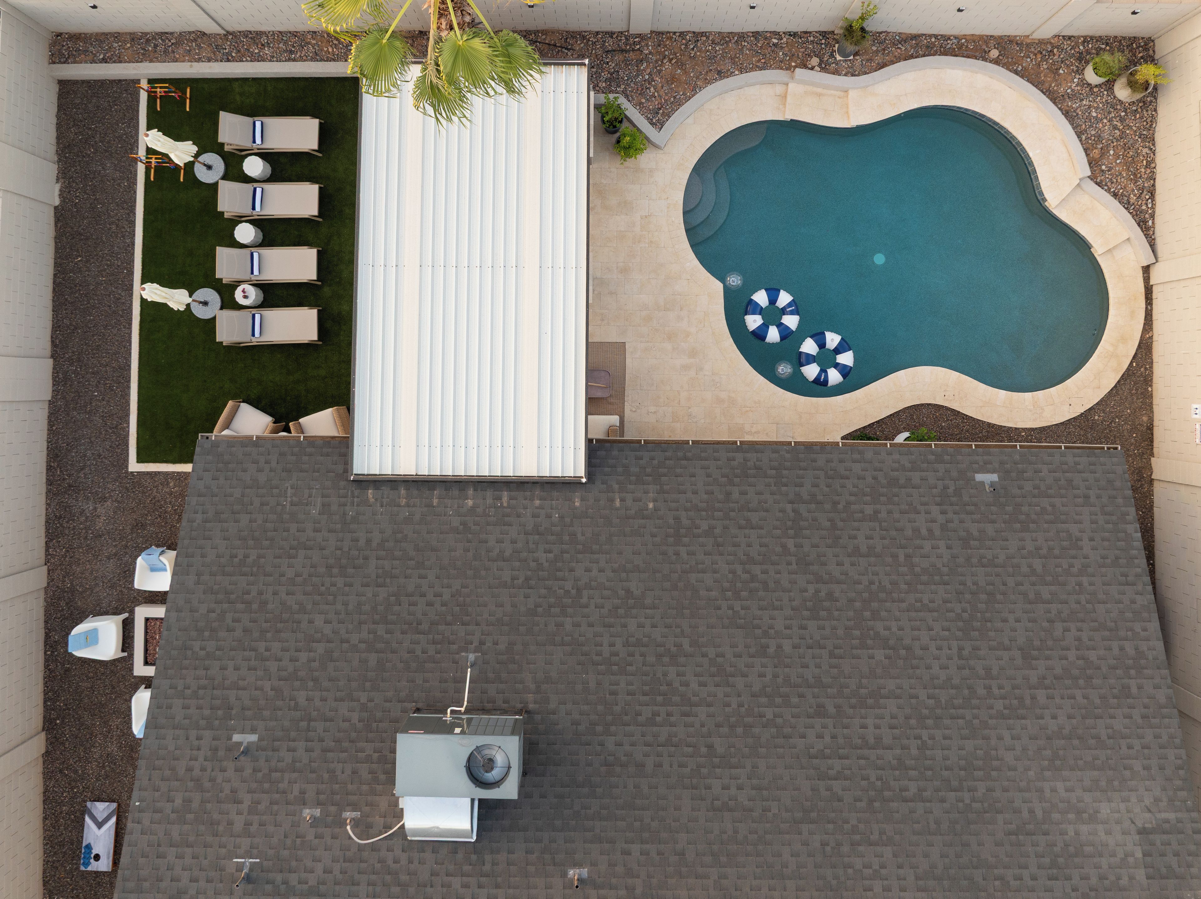 Una piscina en la azotea con sillones de descanso y una pequeña terraza.