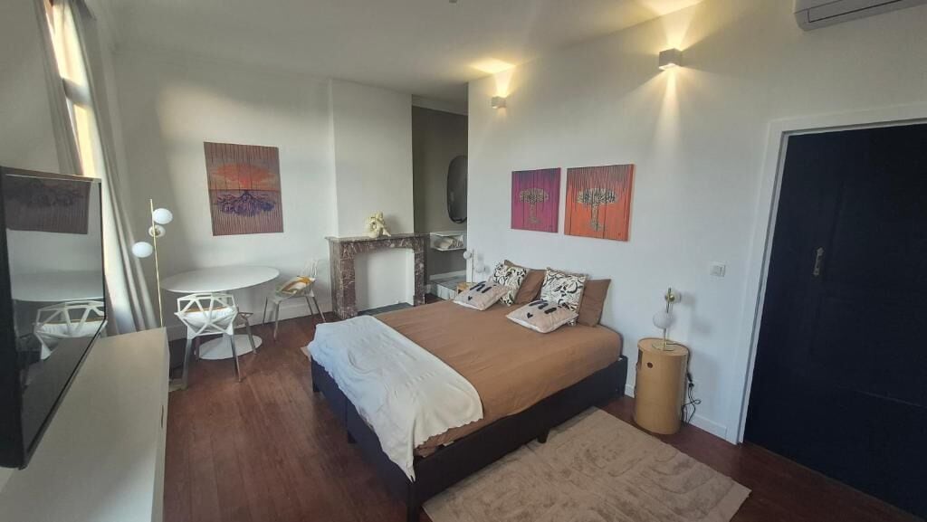 Un dormitorio con cama, mesita de noche, lámpara y obras de arte en las paredes.