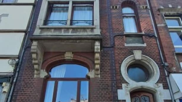 Un edificio de varios pisos con una entrada destacada, amplias ventanas y un letrero que indica un negocio.