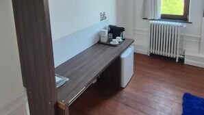 Une pièce avec un plancher en bois, un banc, un radiateur et une fenêtre avec des rideaux.