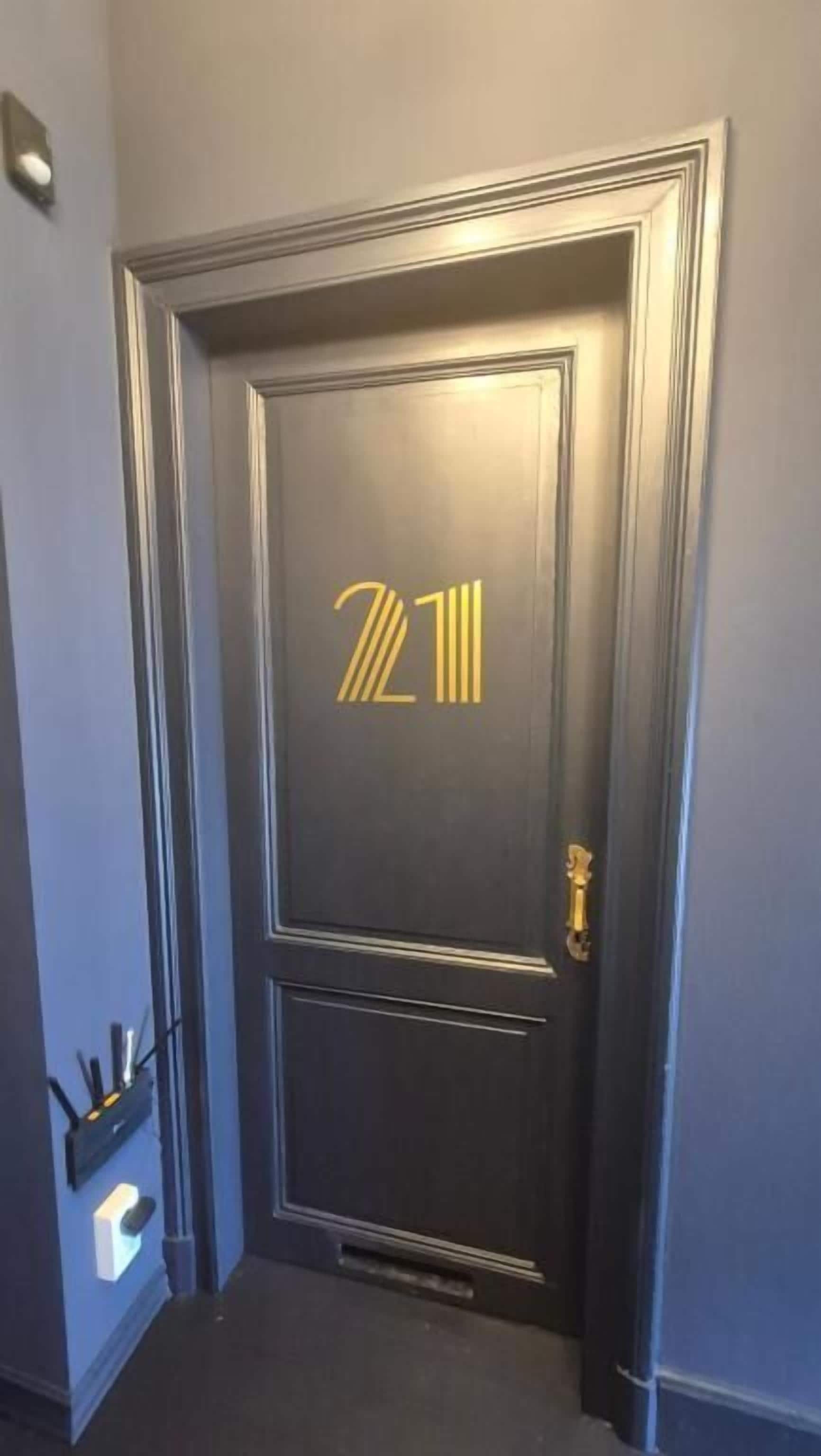 Una puerta de madera oscura con el número '7211' en dorado y una cerradura.