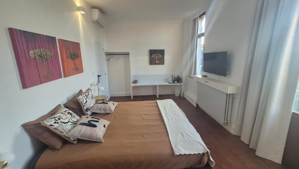 Ein Schlafzimmer mit einem Bett, einem Fernseher, einem Schreibtisch und Kunstwerken an den Wänden.
