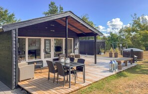 Um terraço moderno ao ar livre com área de refeições, varanda coberta e um pequeno jardim.