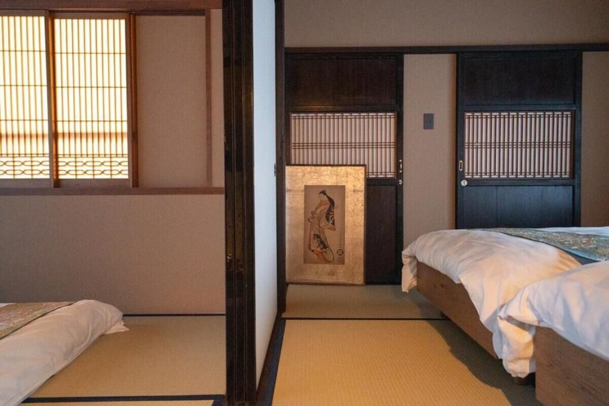 A traditional Japanese room with tatami flooring, a futon bed, sliding doors, and shoji screens.