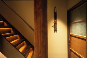 Un escalier en bois mène à une pièce dotée d’une porte et d’un objet fixé au mur.