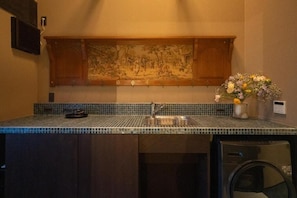 A kitchen with a tiled backsplash, a sink, a dishwasher, and a decorative painting above the countertop. - Kokeiran Kyoto Machiya (Kyoto)