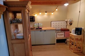 A compact kitchen with a microwave, sink, and wooden cabinets. - Holiday home with 1 bedroom (Neuenkirchen)